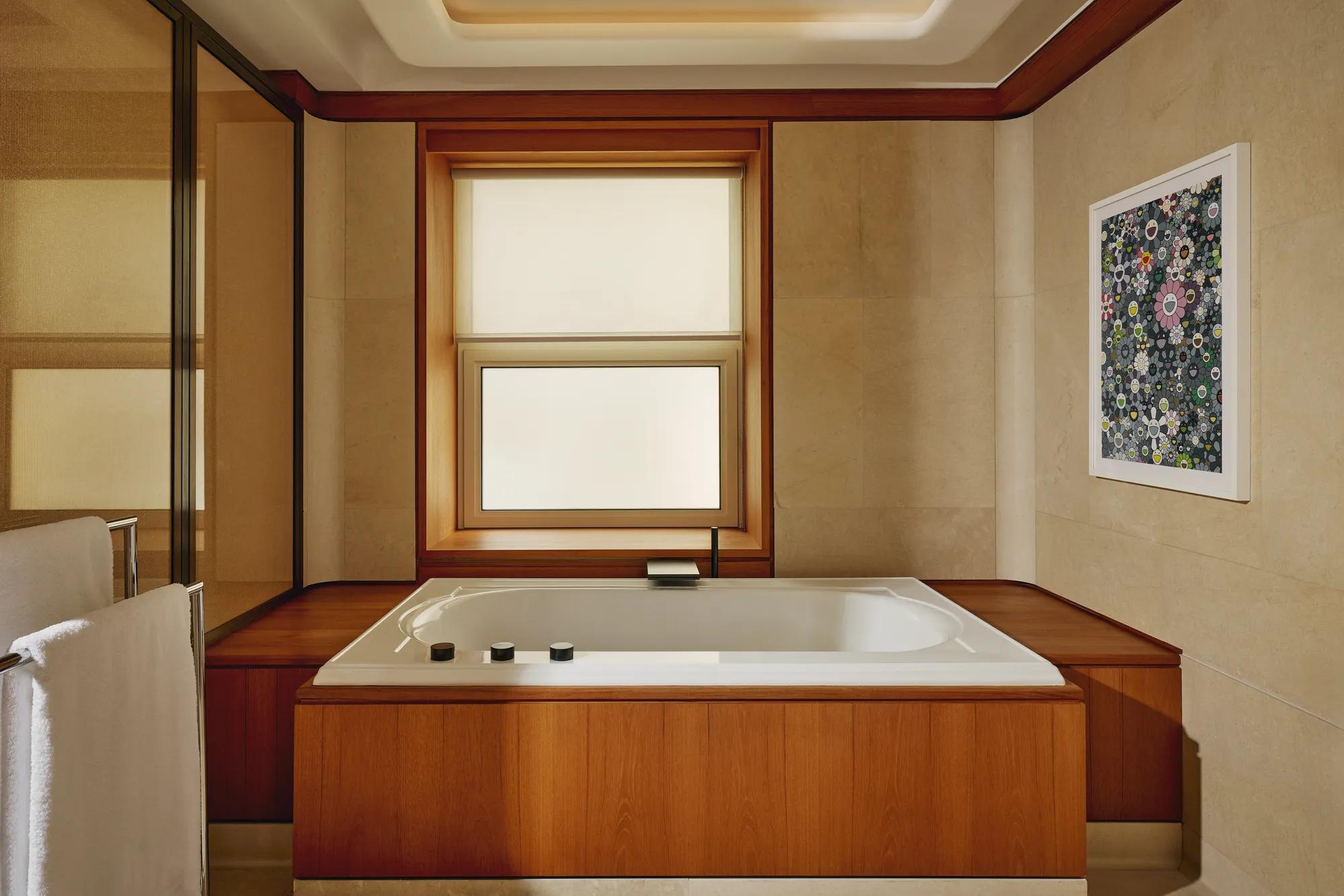 Bathroom with a built-in soaking tub surrounded by warm wood paneling, beige walls, and contemporary floral artwork.
