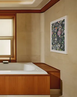Bathroom with a built-in soaking tub surrounded by warm wood paneling, beige walls, and contemporary floral artwork.