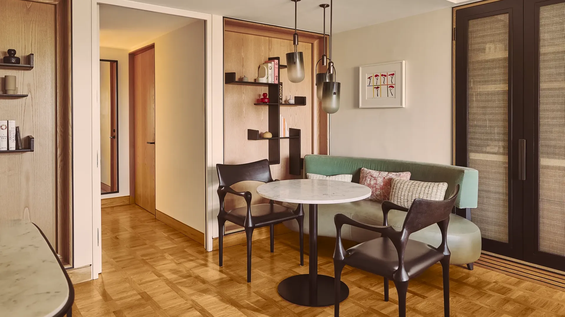Dining nook with round marble table, two chairs, built-in bench seating, and pendant lights.