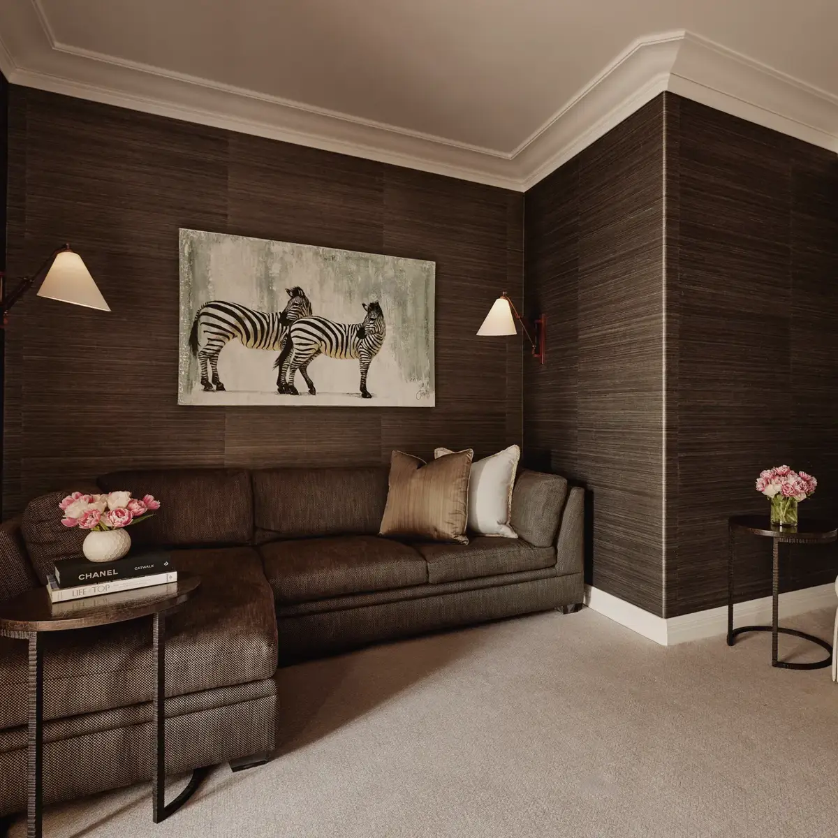 Den or theatre room in Maybourne Beverly Hills three bedroom residence with sectional sofa, armchair, zebra artwork, bookshelves, and side tables.