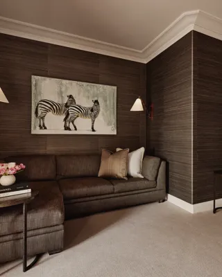 Den or theatre room in Maybourne Beverly Hills three bedroom residence with sectional sofa, armchair, zebra artwork, bookshelves, and side tables.