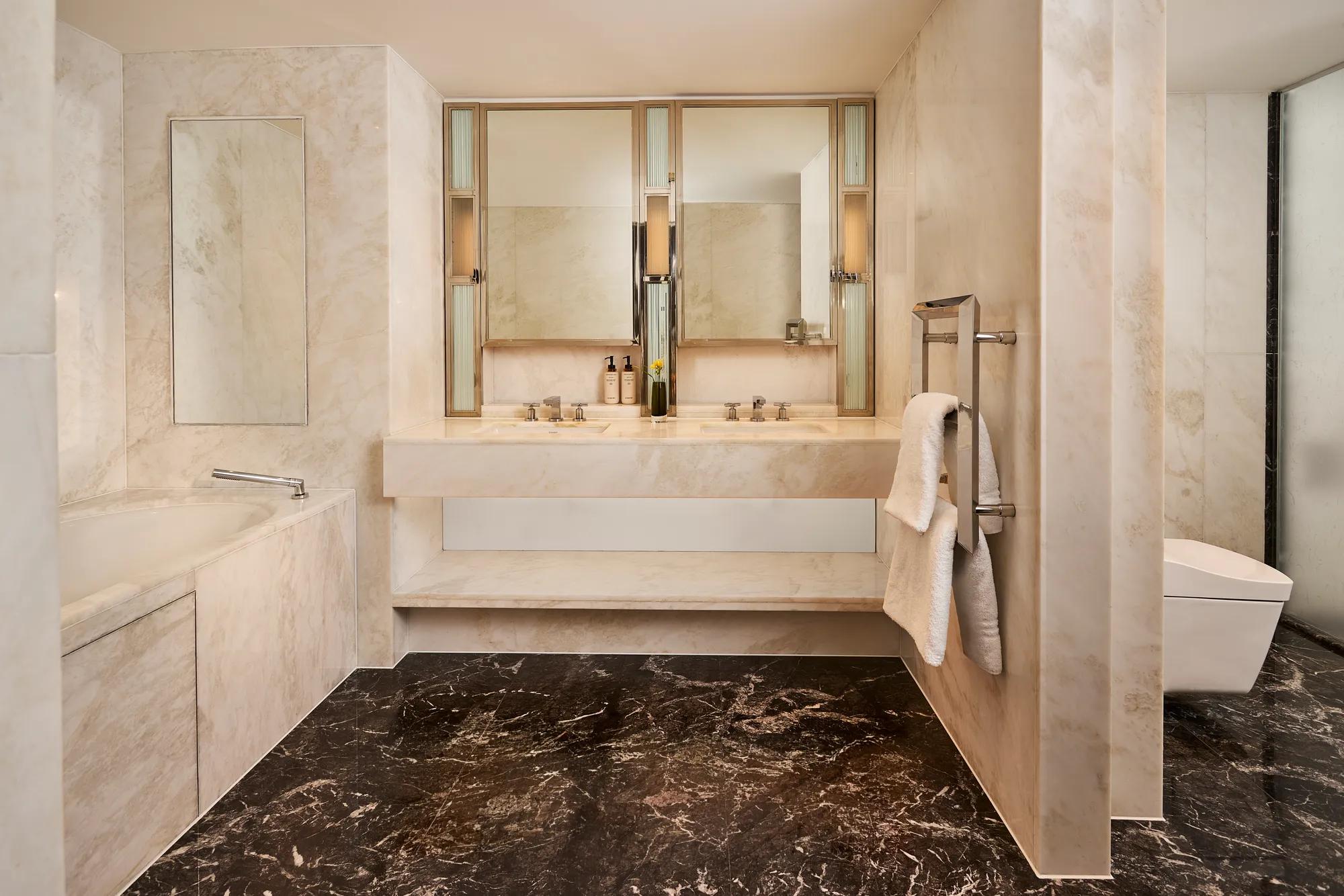 **Alt text:**
Marble bathroom with a double vanity, soaking bath, walk-in shower, separate WC and dark stone flooring.
