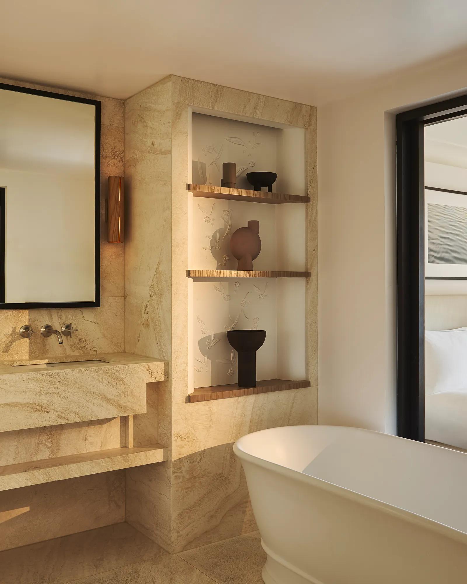 Elegant bathroom featuring white marble floors and walls, a soaking tub and chrome fixtures