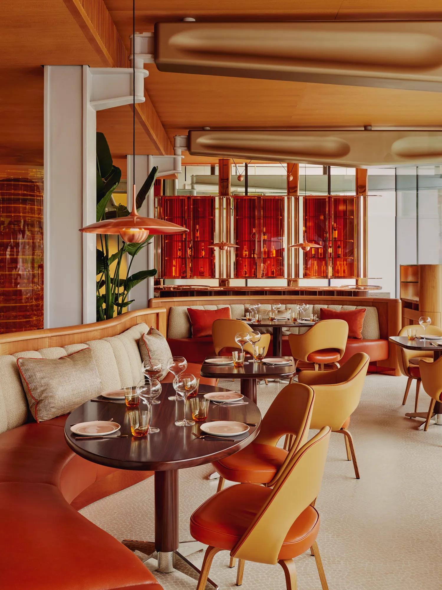 Vibrant dining room with curved banquettes, warm-toned chairs, and contemporary red and orange décor.