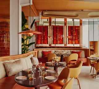 Vibrant dining room with curved banquettes, warm-toned chairs, and contemporary red and orange décor.