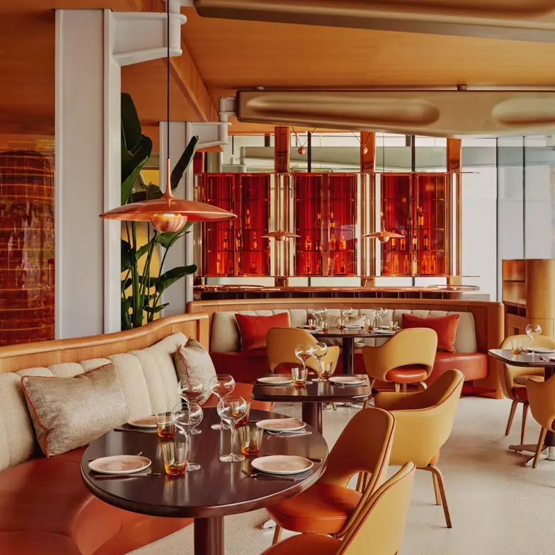 Vibrant dining room with curved banquettes, warm-toned chairs, and contemporary red and orange décor.