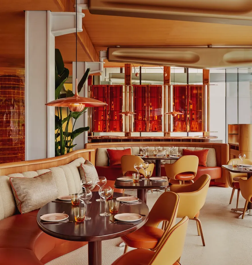Vibrant dining room with curved banquettes, warm-toned chairs, and contemporary red and orange décor.