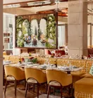 Dining area with yellow upholstered chairs and a large framed photograph of an outdoor terrace scene.