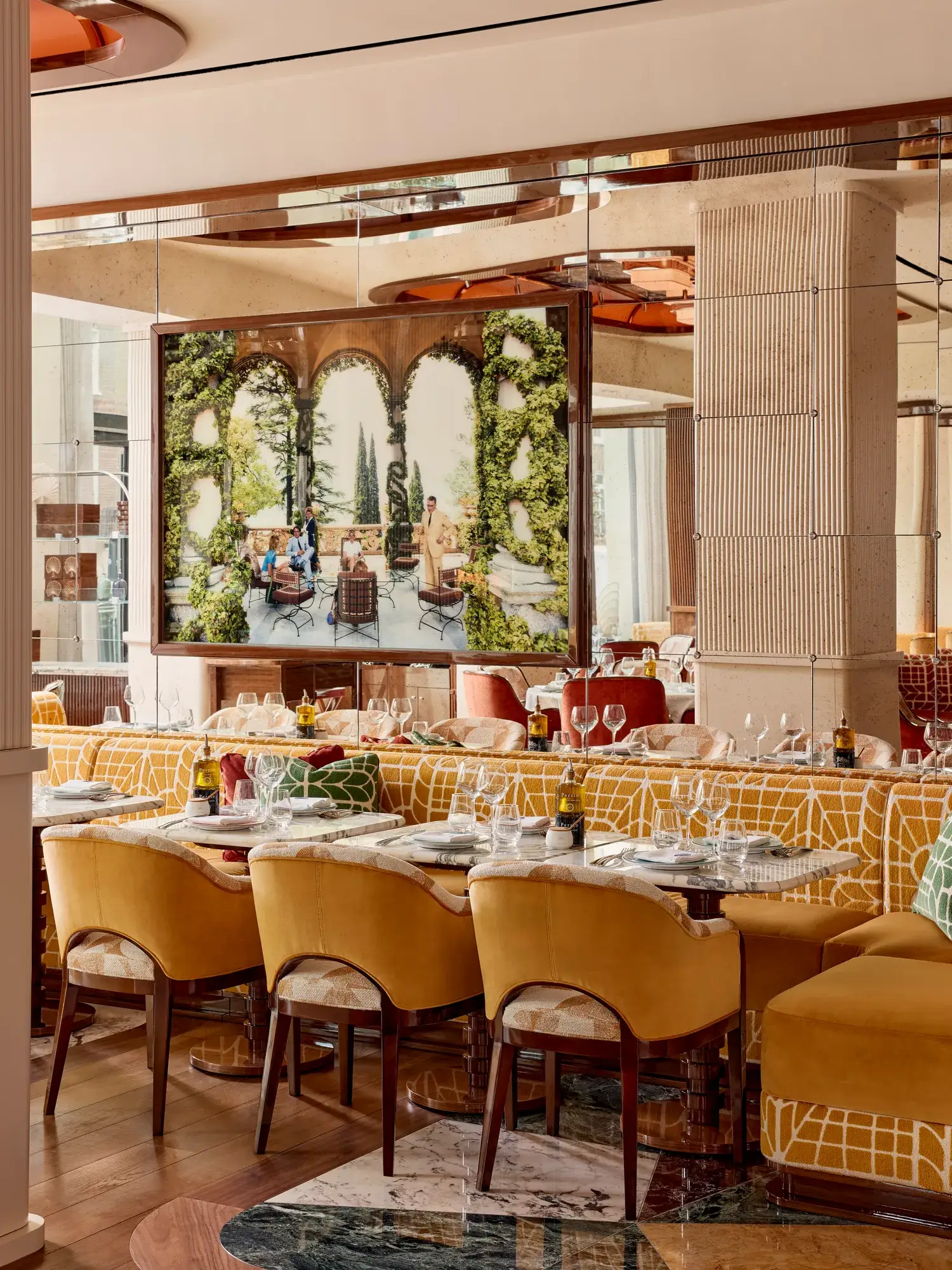 Dining area with yellow upholstered chairs and a large framed photograph of an outdoor terrace scene.