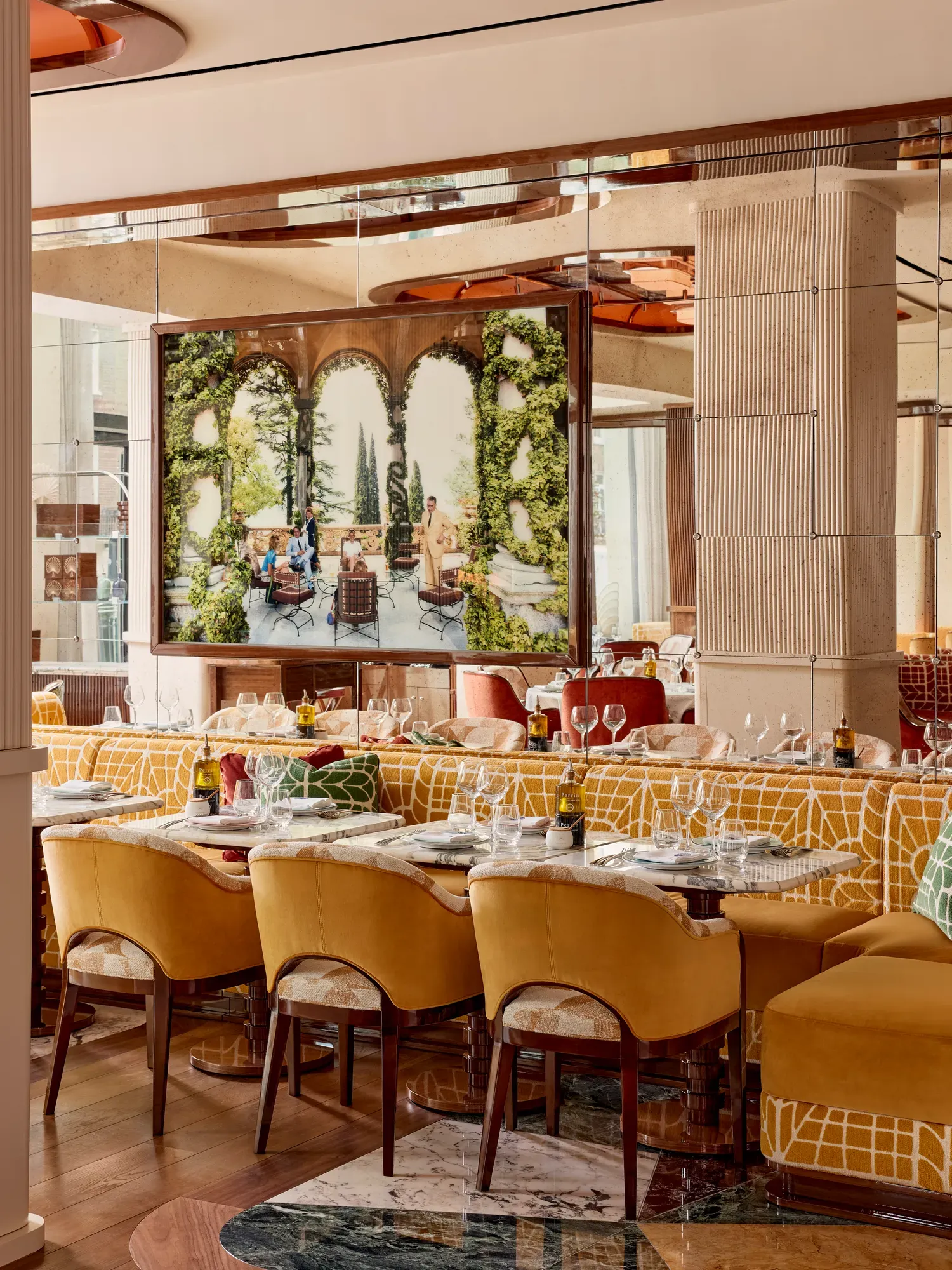 Dining area with yellow upholstered chairs and a large framed photograph of an outdoor terrace scene.