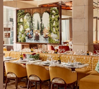 Dining area with yellow upholstered chairs and a large framed photograph of an outdoor terrace scene.