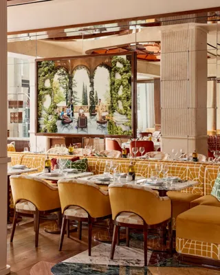 Dining area with yellow upholstered chairs and a large framed photograph of an outdoor terrace scene.