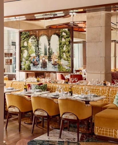 Dining area with yellow upholstered chairs and a large framed photograph of an outdoor terrace scene.