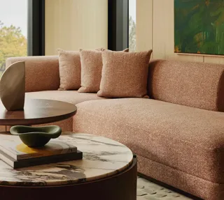 Modern living room with a neutral sectional sofa, large window overlooking green trees.