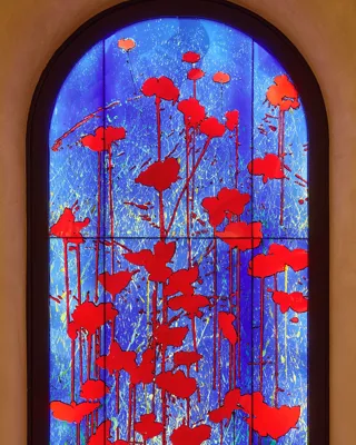 Arched stained-glass-style panel with vivid red poppy silhouettes against a glowing blue background.