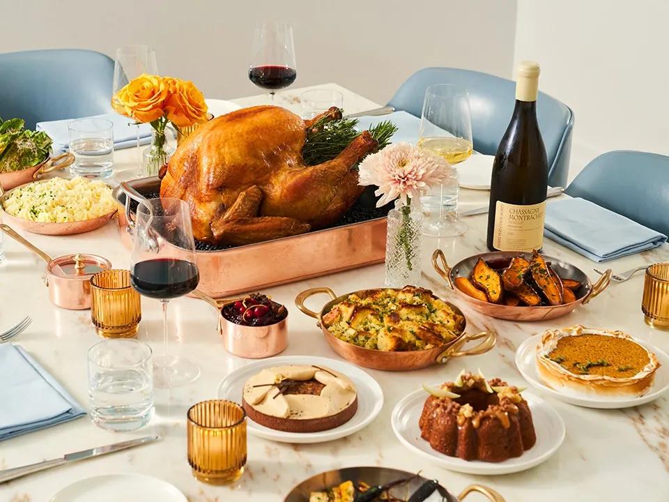 Roast turkey surrounded by seasonal sides, desserts, wine, and candlelight on an elegantly set festive dining table.