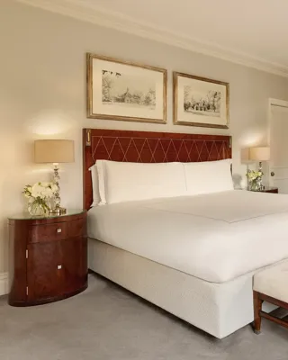 Spacious bedroom featuring a king-size bed with a polished wooden headboard, mirrored wardrobes, and neutral-toned furnishings.
