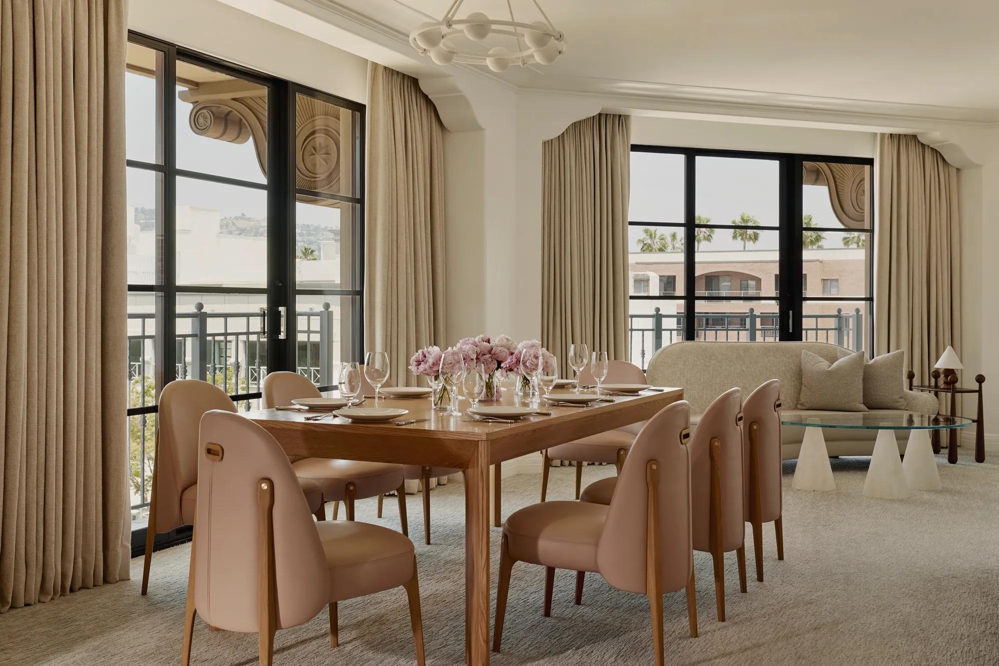 Expansive dining area in the Garden Suite with wooden table, blush chairs, flowers, and large windows.