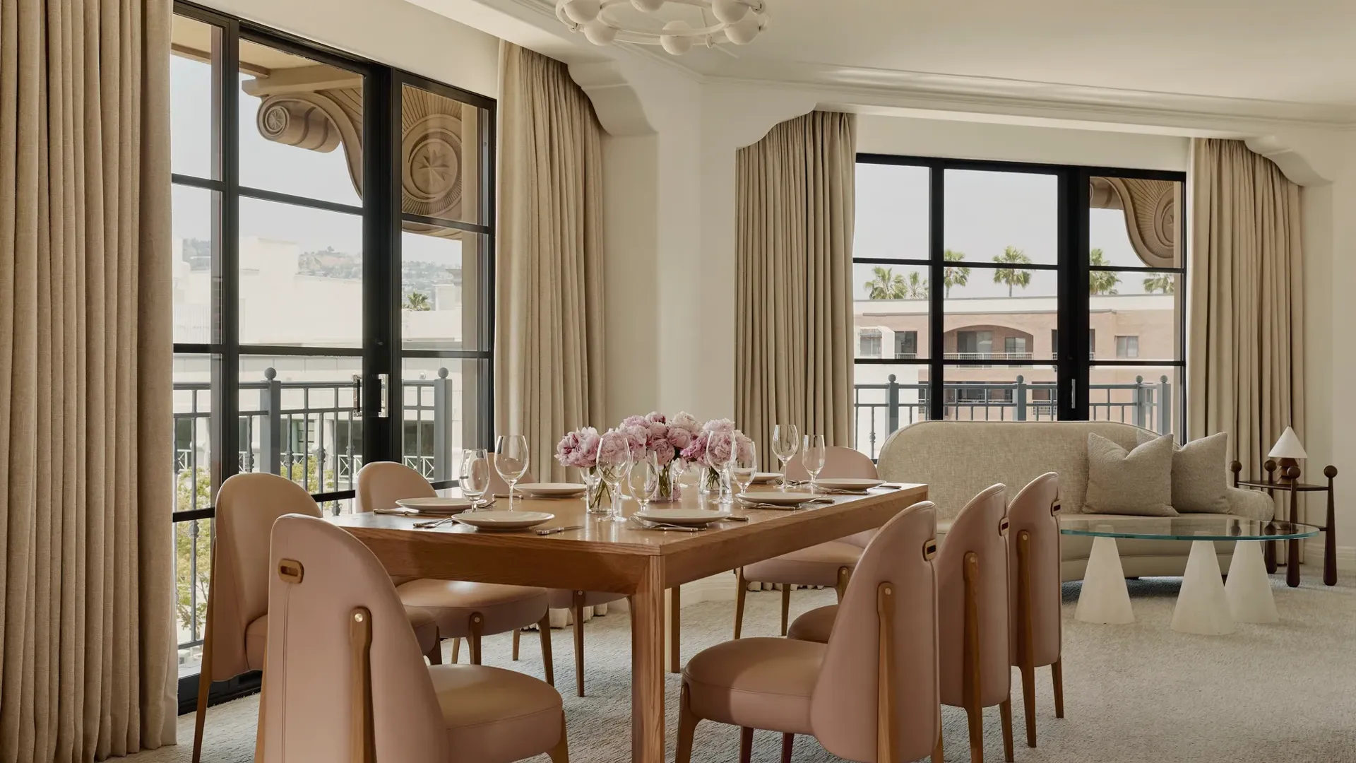Expansive dining area in the Garden Suite with wooden table, blush chairs, flowers, and large windows.