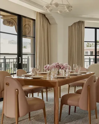 Expansive dining area in the Garden Suite with wooden table, blush chairs, flowers, and large windows.