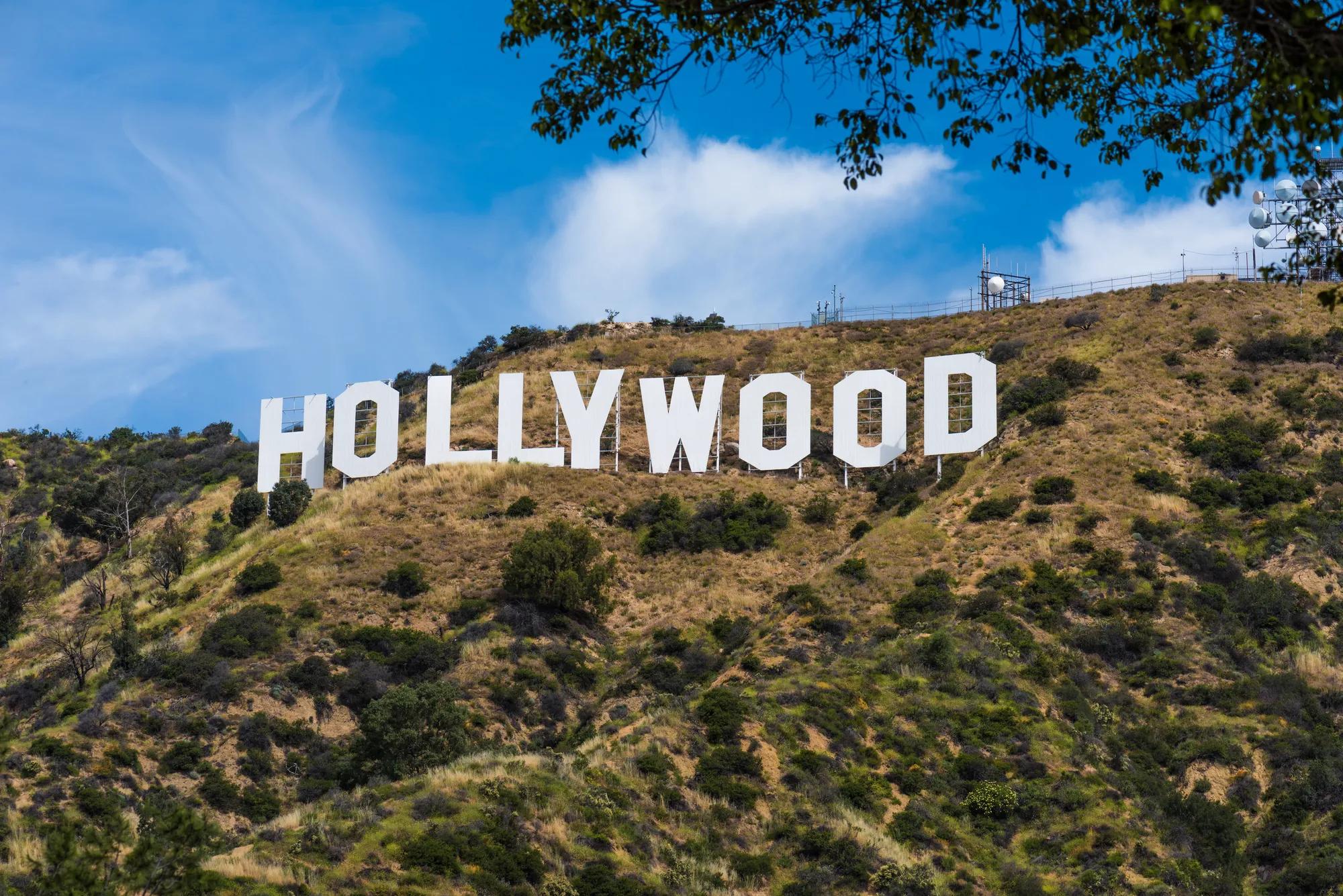 The Hollywood sign on a sunlit hillside under a bright blue sky.