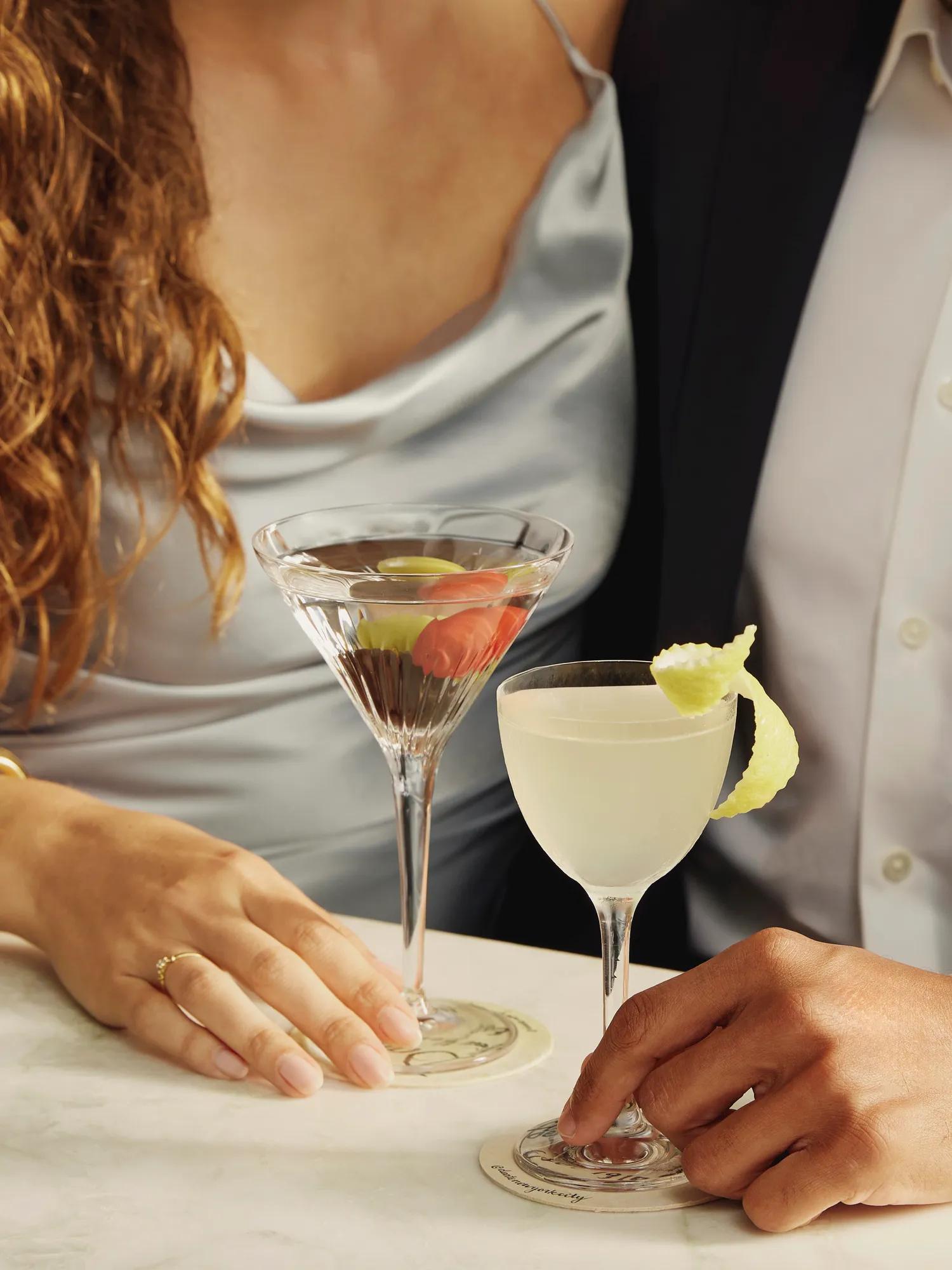 Couple holding martini and cocktail at a marble table at Dante rooftop restaurant
