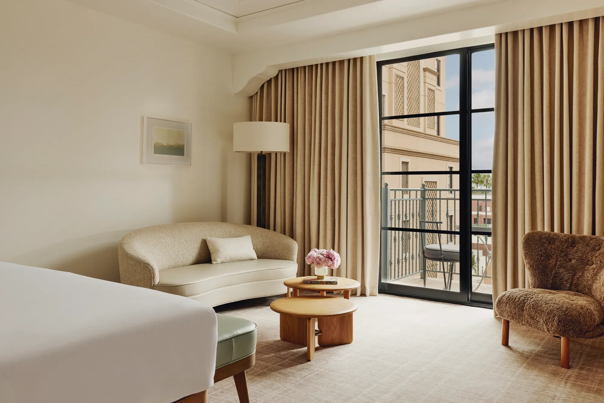 Elegant hotel room with king bed, neutral tones, and balcony doors.