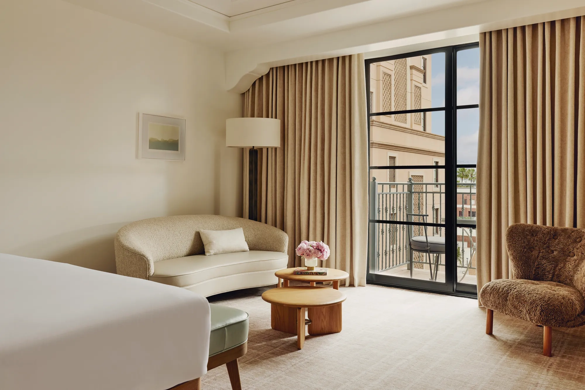 Elegant hotel room with king bed, neutral tones, and balcony doors.