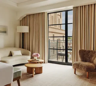 Elegant hotel room with king bed, neutral tones, and balcony doors.