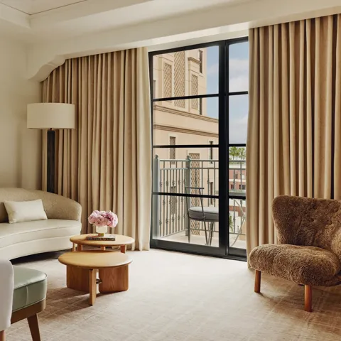 Elegant hotel room with king bed, neutral tones, and balcony doors.