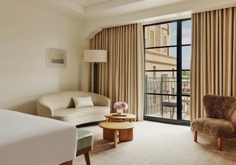Elegant hotel room with king bed, neutral tones, and balcony doors.