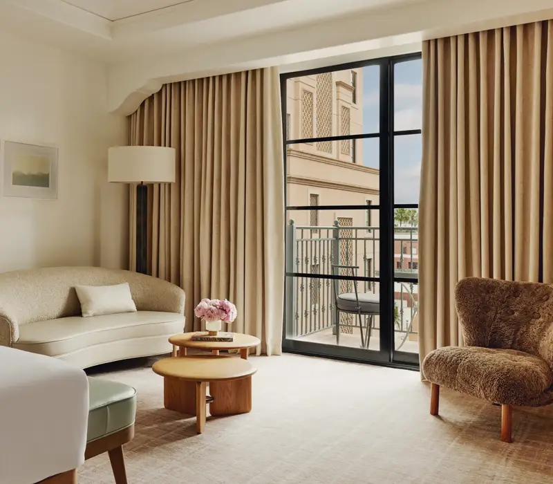 Elegant hotel room with king bed, neutral tones, and balcony doors.
