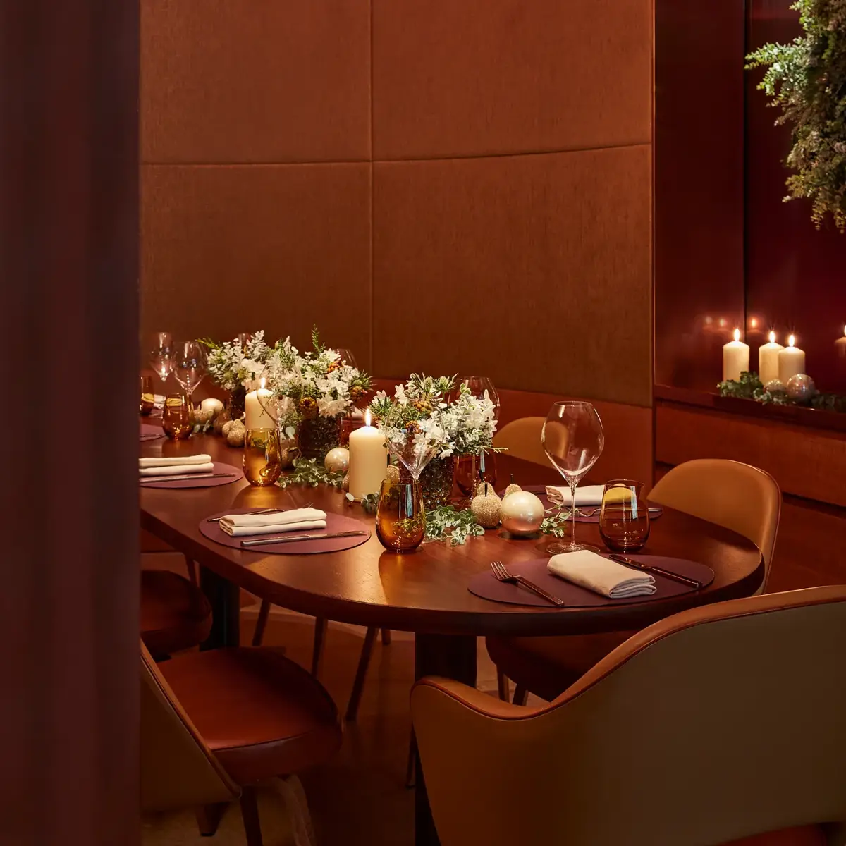 Intimate dining table set with flowers, candles, and glassware in a warm, softly lit private dining room.