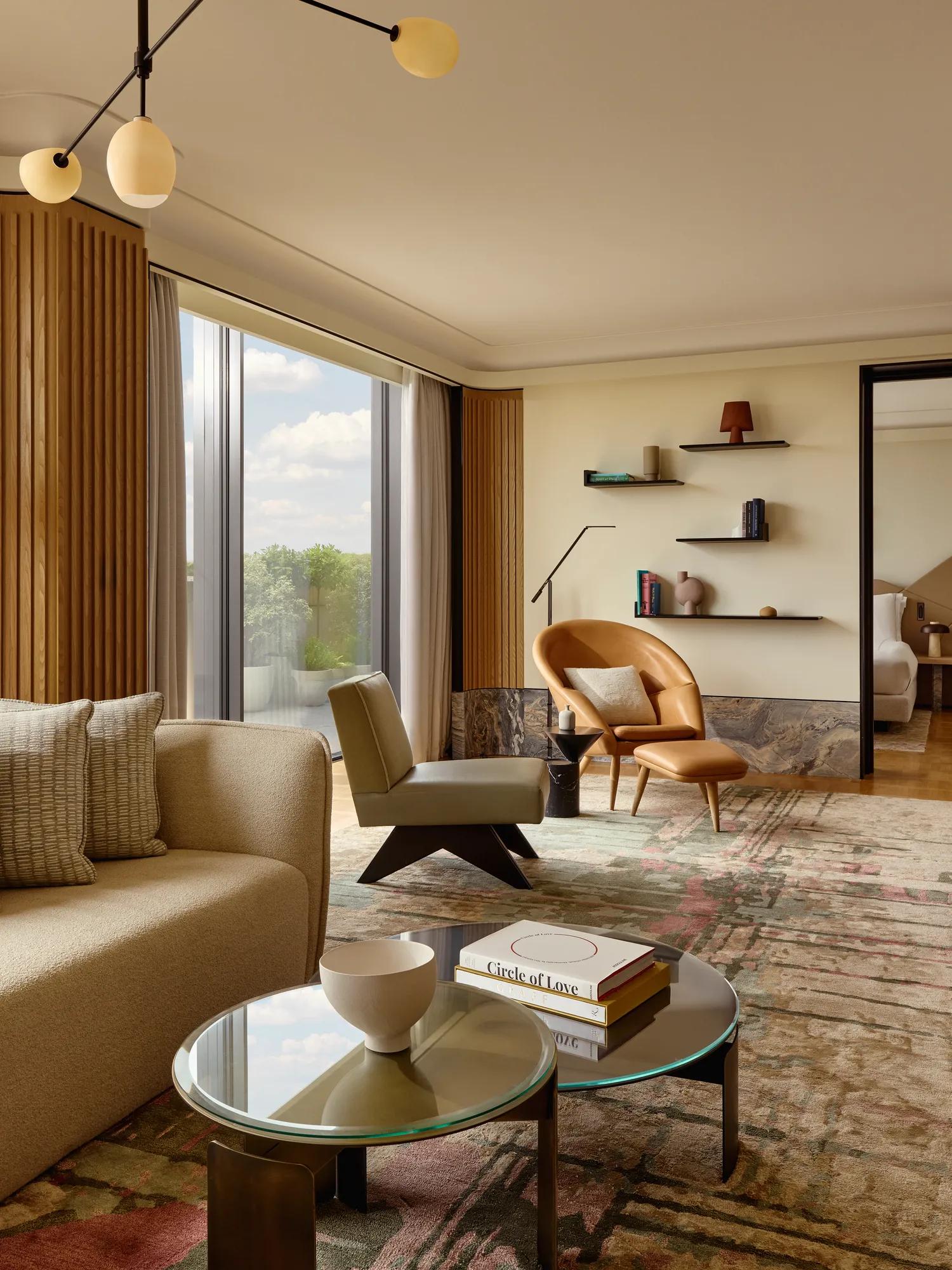 Spacious living room with a cream sofa, leather armchair, and designer lighting, set beside floor-to-ceiling windows overlooking Hyde Park.