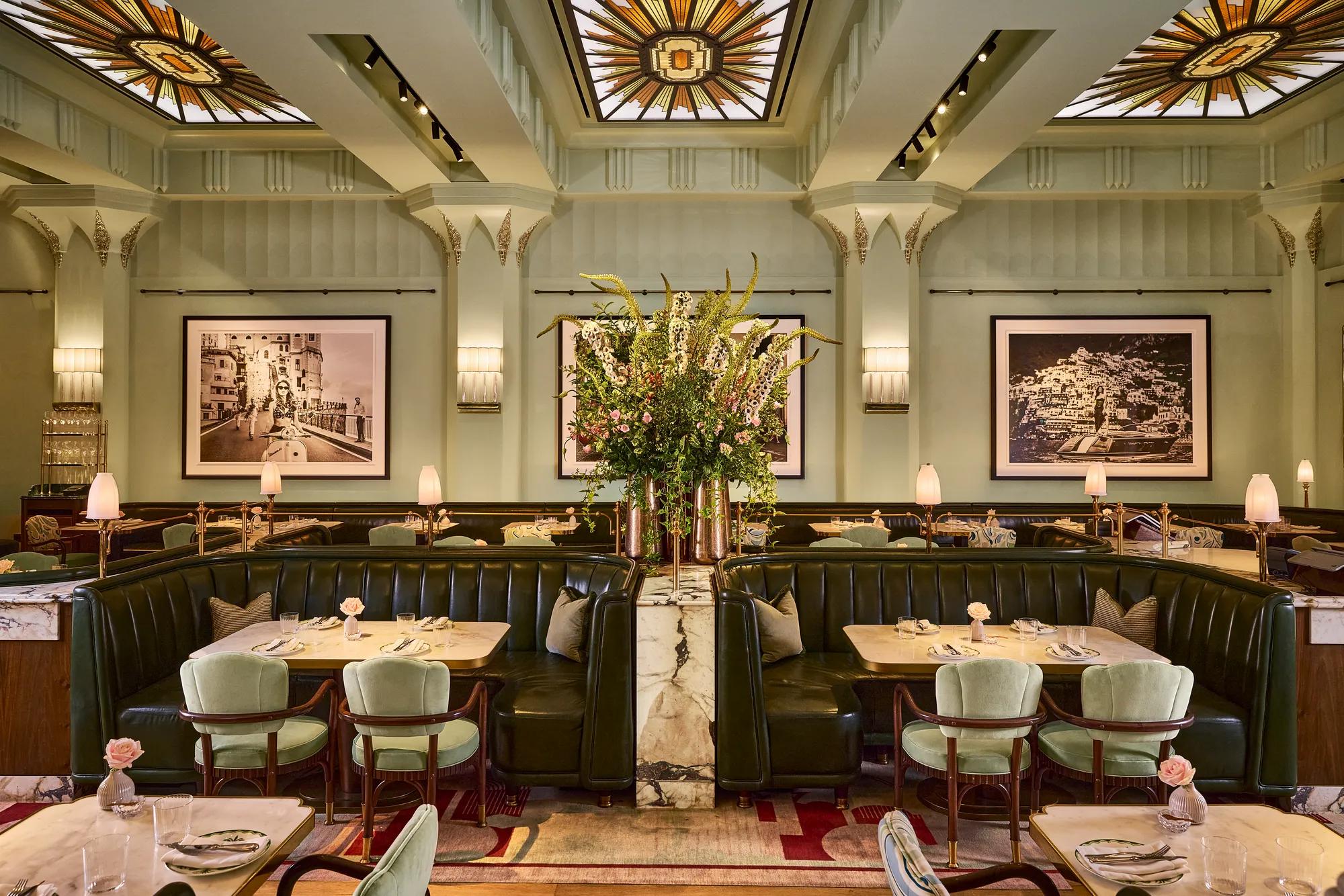 Elegant Art Deco restaurant dining room with leather banquettes, marble tables, floral centrepiece and decorative skylights.