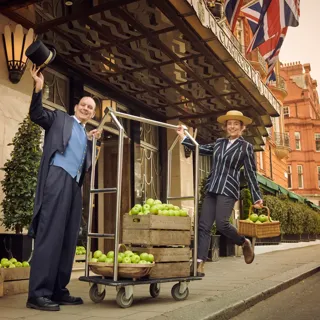 Claridge's hotel entrance with Union flags, staff, and crates of green apples outside.
