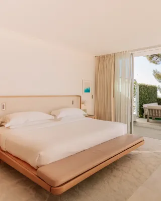 Chambre lumineuse avec lit king-size et coin salon ouvrant sur une terrasse privée avec vue mer.
