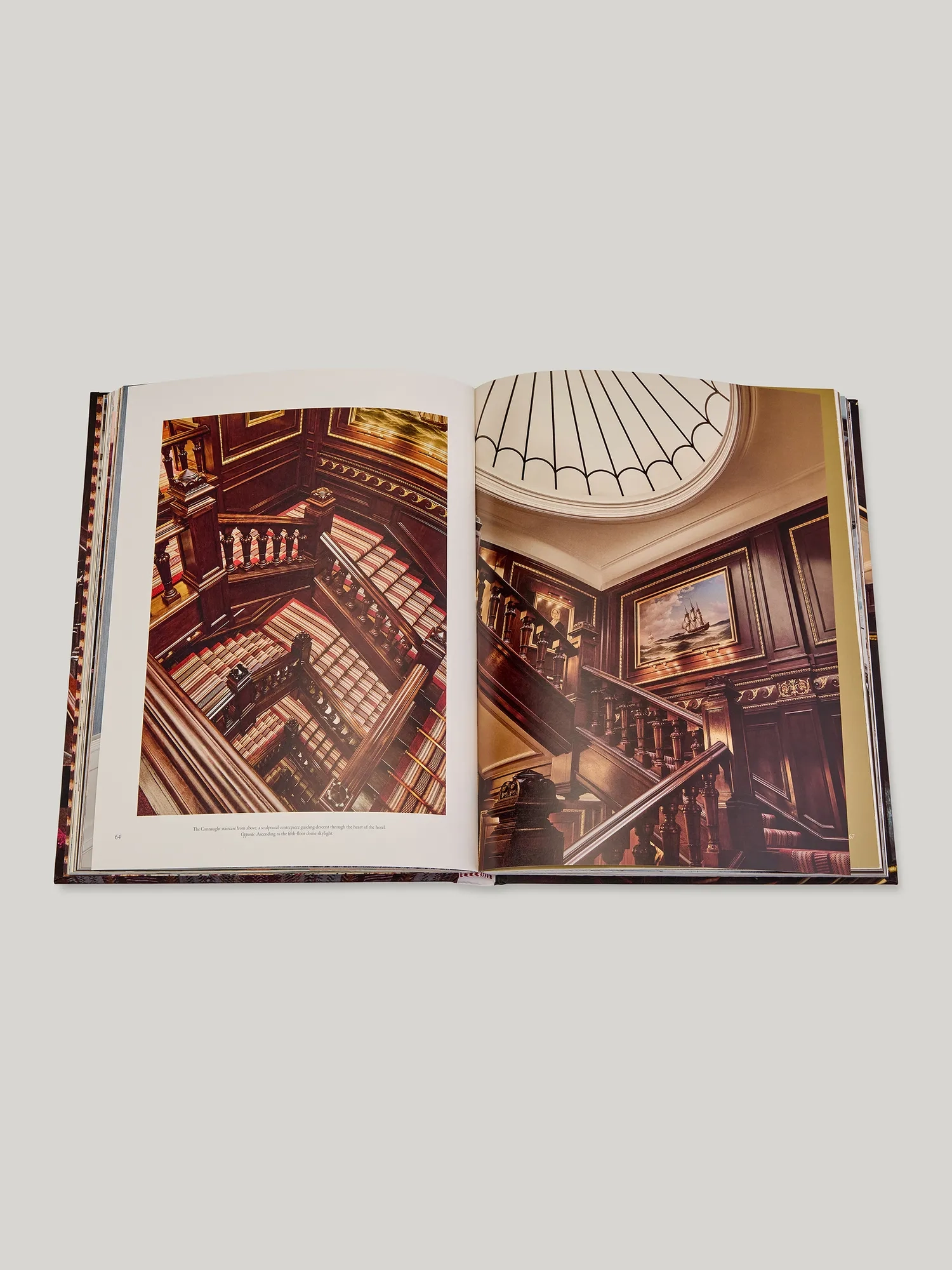 Open book spread showing The Connaught’s grand wood-panelled staircase and skylit atrium from above.