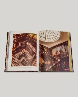Open book spread showing The Connaught’s grand wood-panelled staircase and skylit atrium from above.