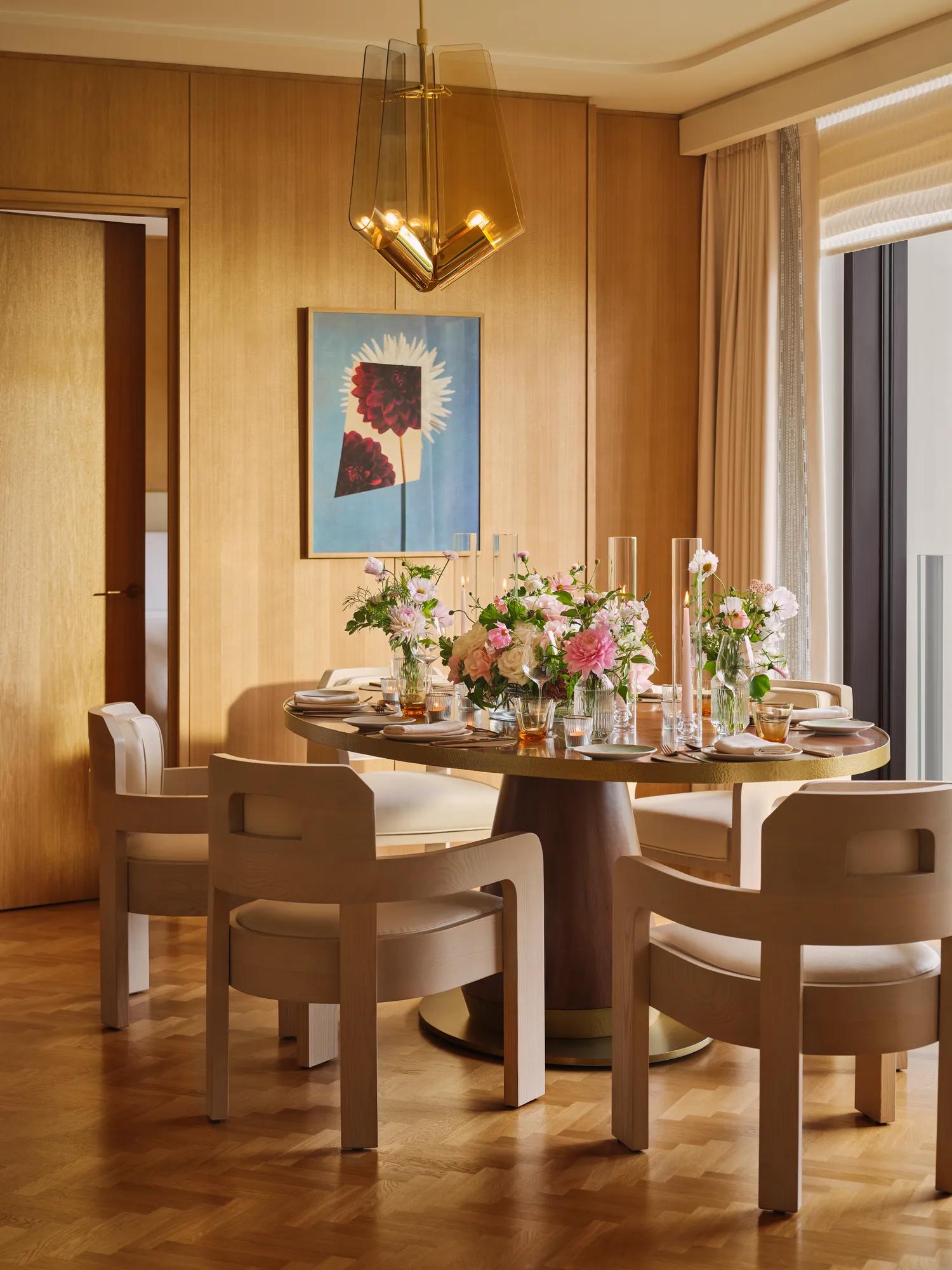 Private dining room set for an elegant meal with floral centrepieces, soft lighting and mid-century modern chairs