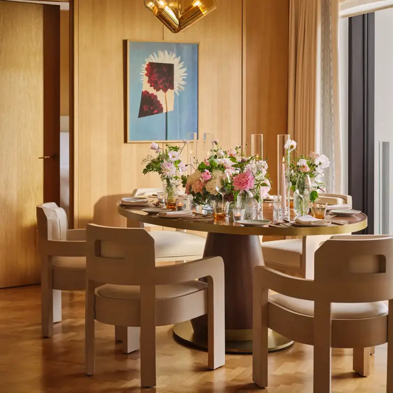 Private dining room set for an elegant meal with floral centrepieces, soft lighting and mid-century modern chairs