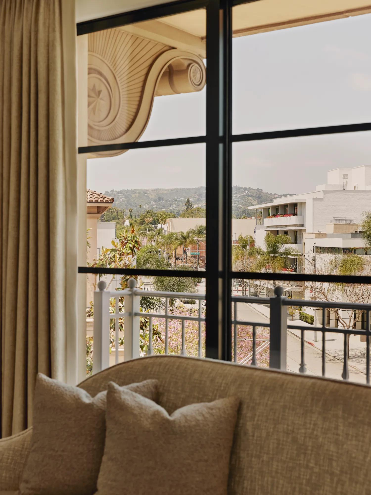 White sofa positioned in front of large windows with a sweeping view over the hills of Beverly Hills