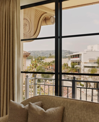 White sofa positioned in front of large windows with a sweeping view over the hills of Beverly Hills