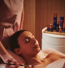 A person lying on a treatment table while a practitioner provides care in a clean, well‑lit room.