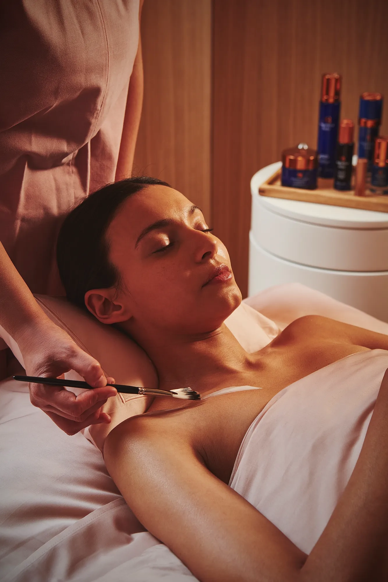 A person lying on a treatment table while a practitioner provides care in a clean, well‑lit room.