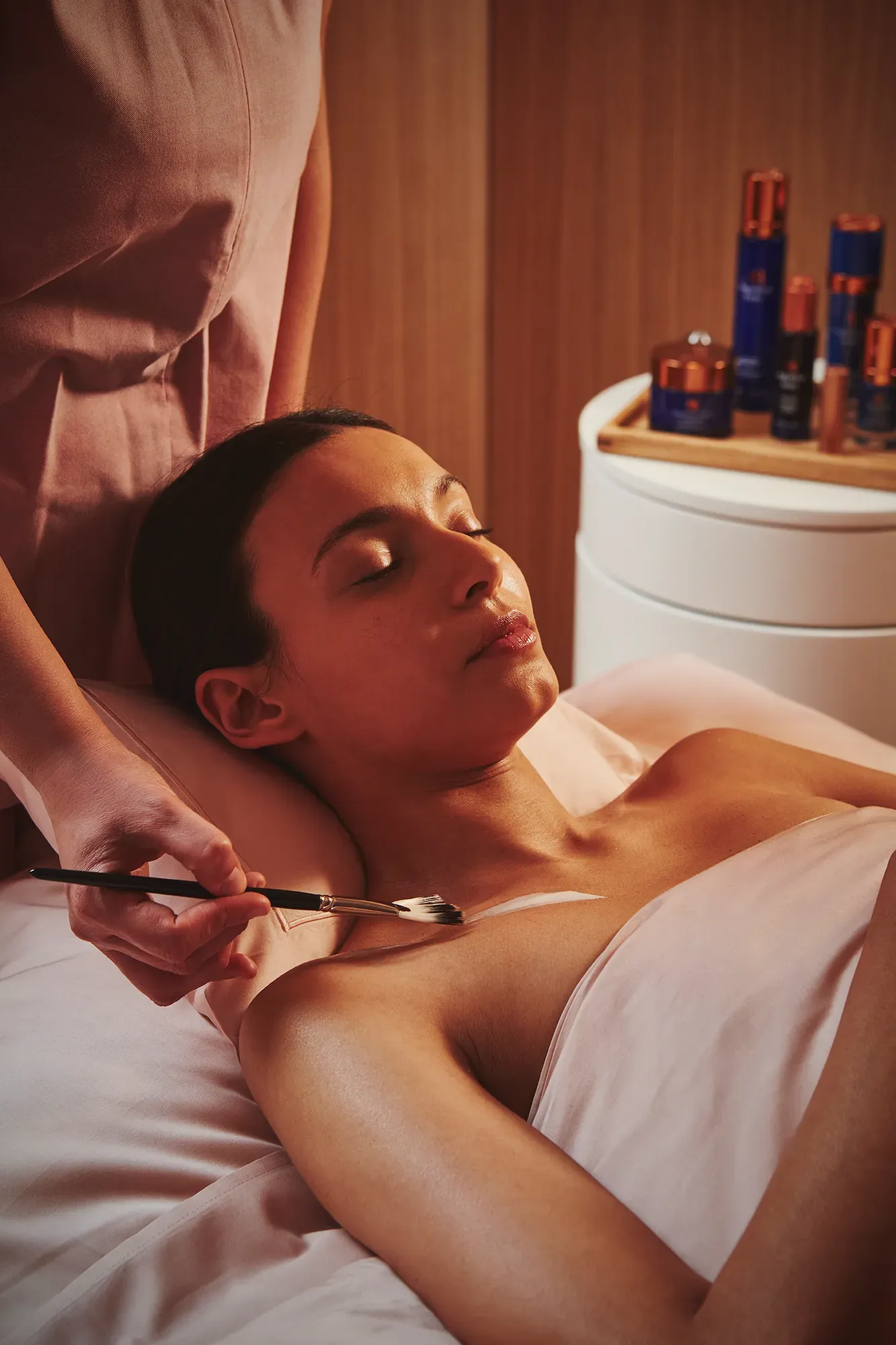 A person lying on a treatment table while a practitioner provides care in a clean, well‑lit room.