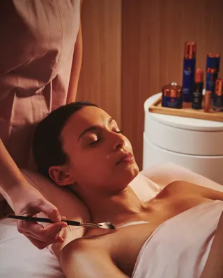 A person lying on a treatment table while a practitioner provides care in a clean, well‑lit room.