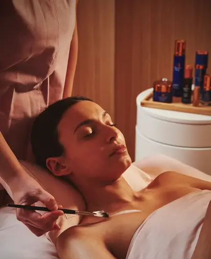 A person lying on a treatment table while a practitioner provides care in a clean, well‑lit room.