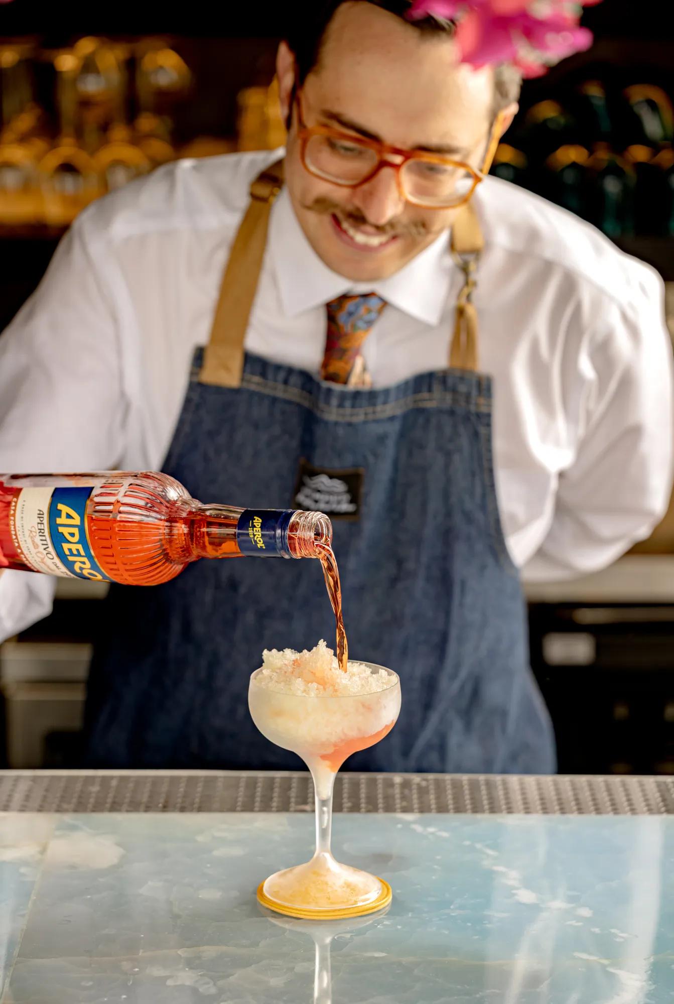 A bartender pouring Aeperol into a glass