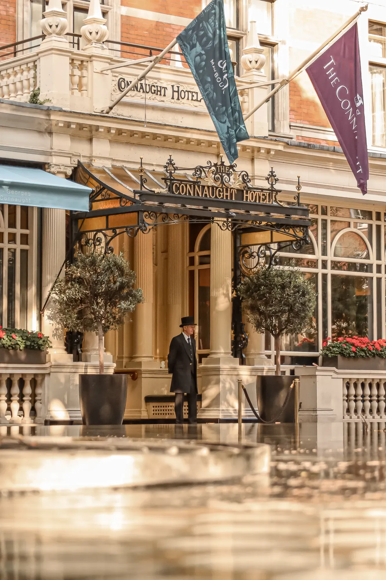 Entrance of The Connaught hotel with its signature canopy and flags above the doorway.